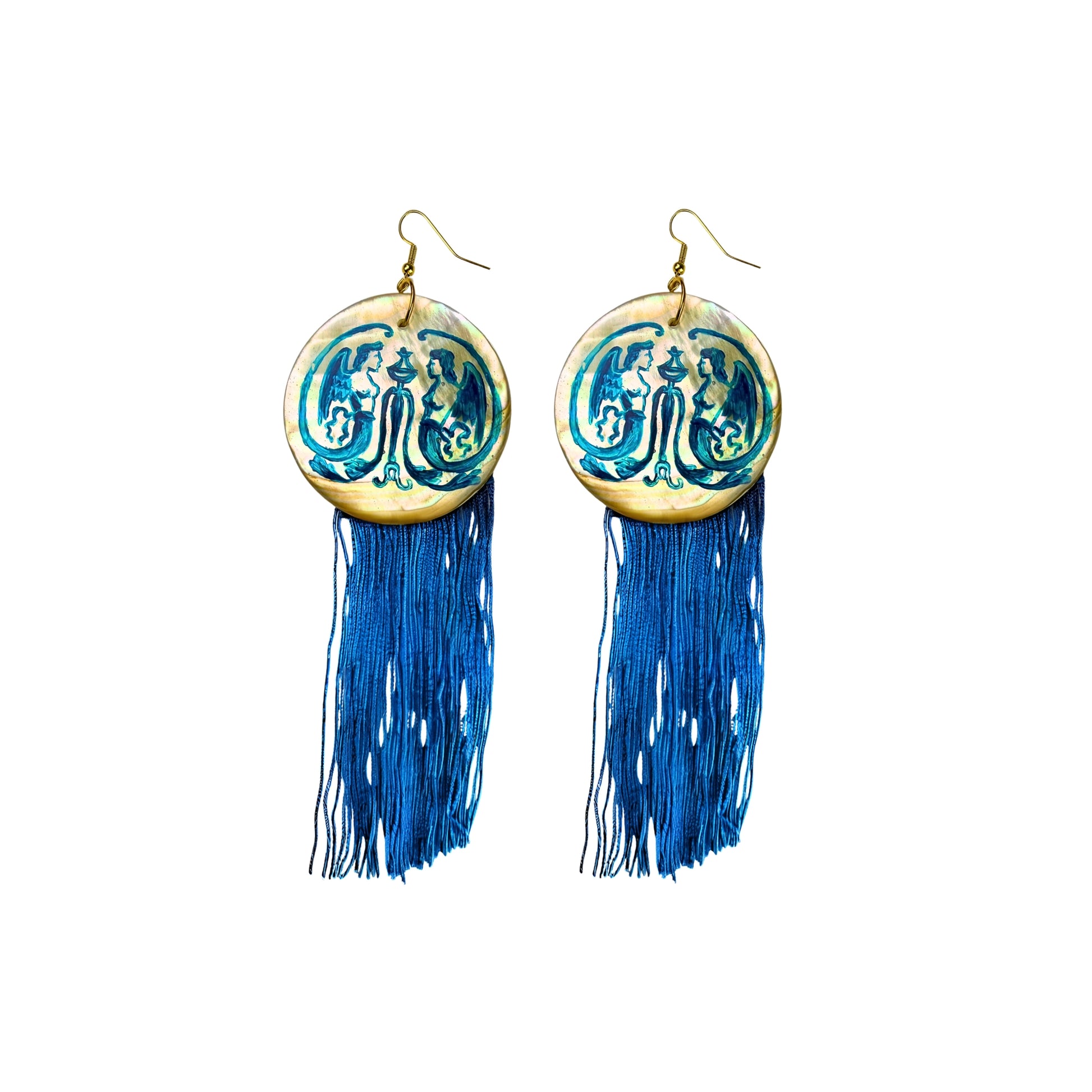 Hand-painted Gemini Mythos statement earrings by Aeterlistá. Large natural mother-of-pearl shell discs featuring symmetrical blue mythological winged figures, finished with long azure blue silk fringe tassels and gold hardware.